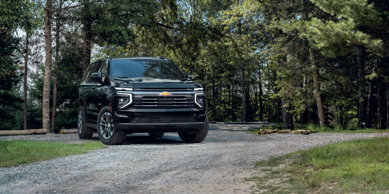 2027 Chevrolet Tahoe in Black parked on a wooded gravel trail